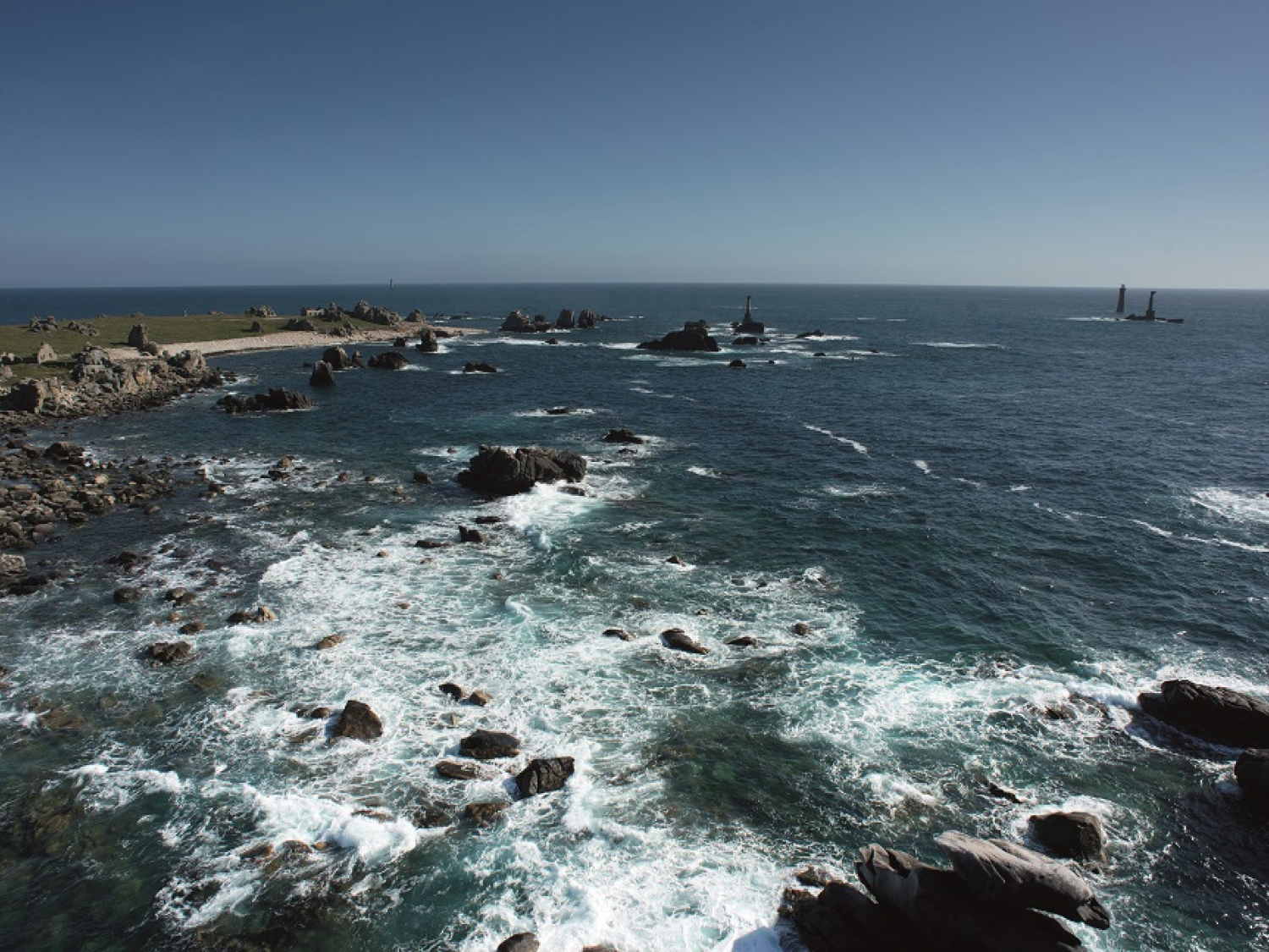 Les côtes de l'île d'Ouessant vues du ciel : pointe de Pern et en arrière plan, le phare de Nividic qui se découvre. Crédit photo : Nicolas Job