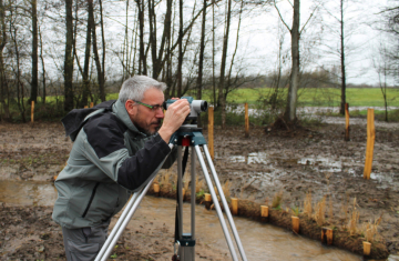 Contrôle des mesures de compensation sur le projet de l’A304 dans la région Grand Est. Utilisation d’un théodolite pour mesurer la pente du cours d’eau. Crédit photo : Lucinda Aissani / OFB