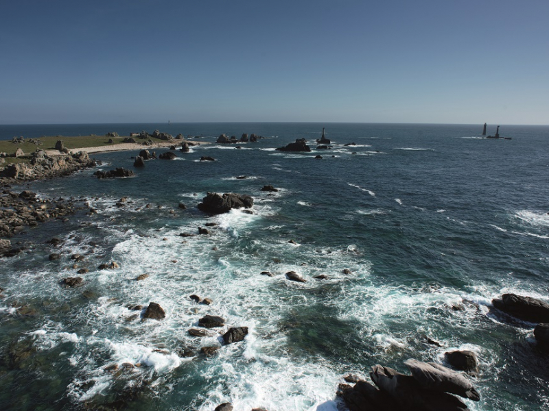 Les côtes de l'île d'Ouessant vues du ciel : pointe de Pern et en arrière plan, le phare de Nividic qui se découvre. Crédit photo : Nicolas Job